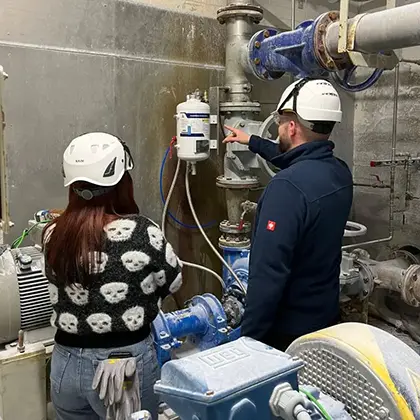 An office worker and an engineer inspect a system together on site.